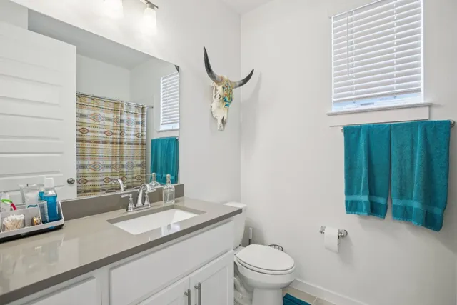 a bathroom with a granite countertop sink a toilet and a window