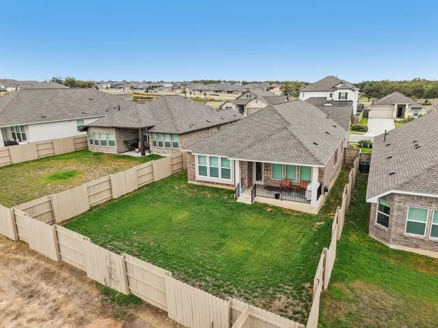 an aerial view of residential houses with outdoor space and trees