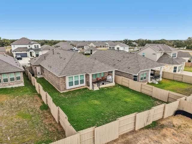 an aerial view of residential houses with outdoor space and trees