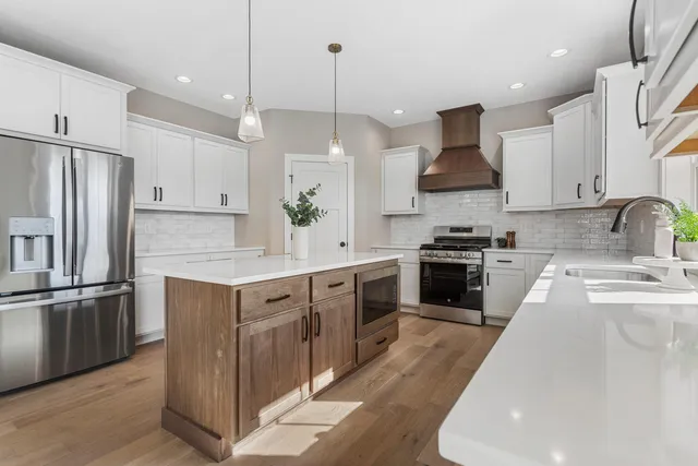 a kitchen with kitchen island granite countertop a sink a counter space stainless steel appliances and cabinets