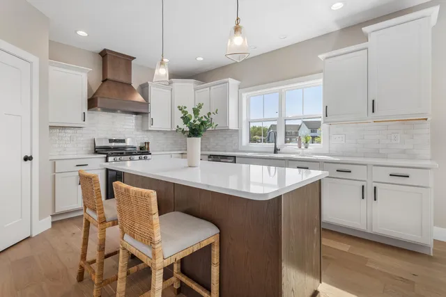 a kitchen with stainless steel appliances granite countertop a table chairs sink and cabinets