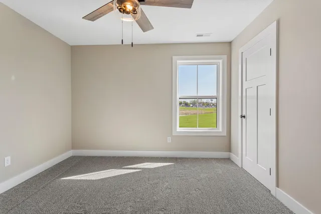 an empty room with a window and a ceiling fan