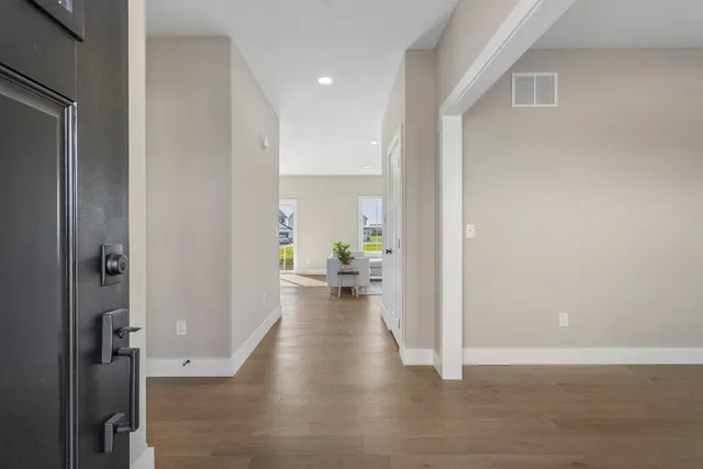 a view of a hallway with wooden floor and a living room