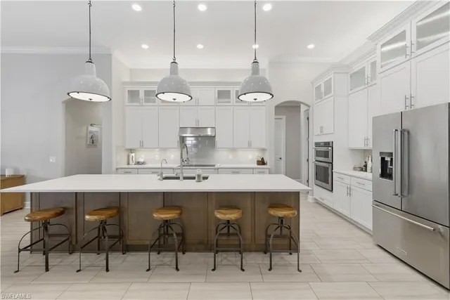 a kitchen with a sink a center island stainless steel appliances and cabinets