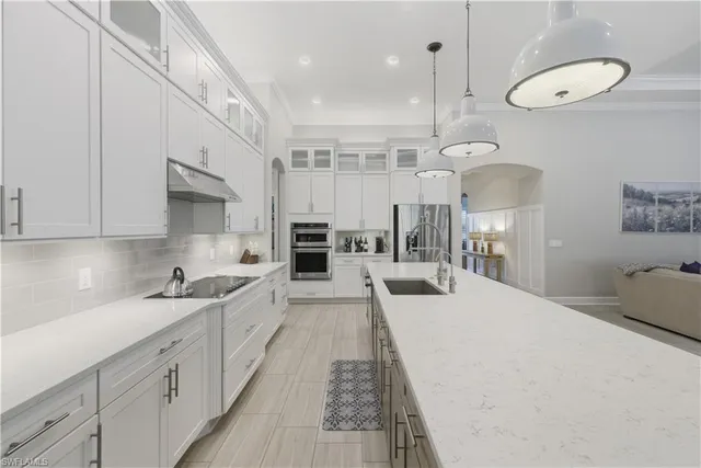 a large white kitchen with a sink a dishwasher a stove and a refrigerator with wooden floor