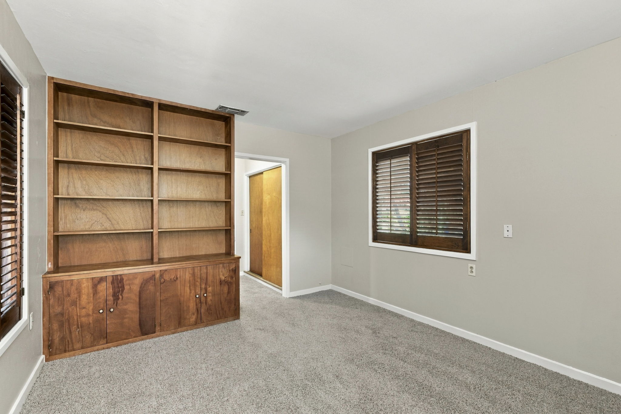 2303 Kinney Road Austin, TX 78704 - Photo 11 of 17 A spacious room features plush carpeting and a large built-in wooden bookcase.