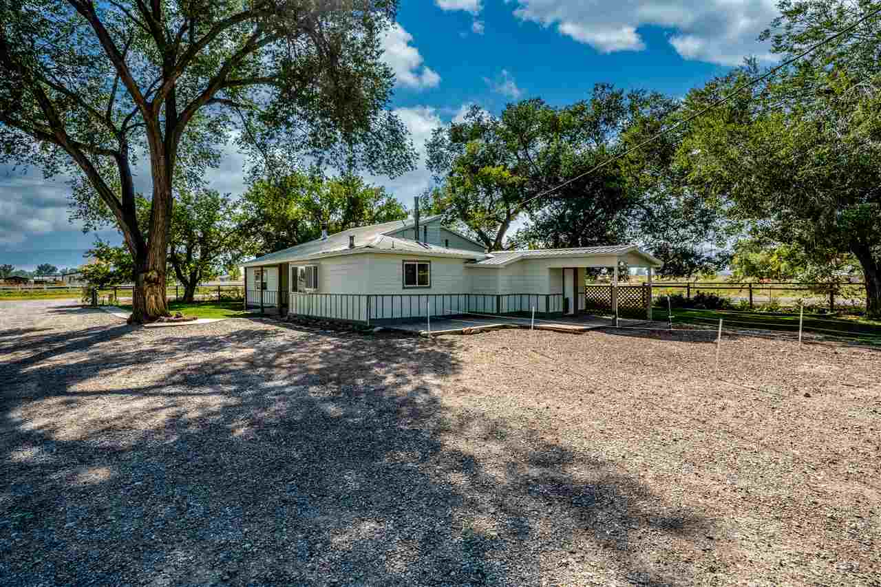 2052 I Road Fruita, CO 81521 - Photo 4 of 31 a backyard of a house with large trees and outdoor seating