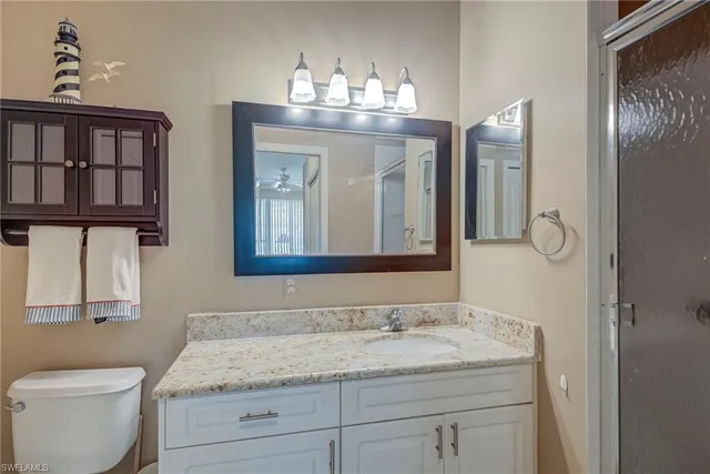 a bathroom with a granite countertop sink a toilet and a mirror