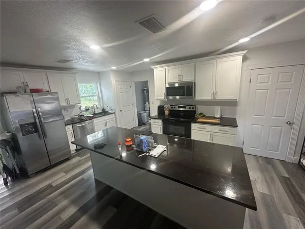a kitchen with stainless steel appliances granite countertop a refrigerator a stove a sink dishwasher a dining table and chairs with wooden floor