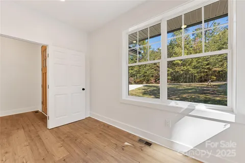 a view of an empty room with wooden floor and windows