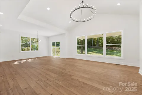 a view of an empty room with wooden floor and window