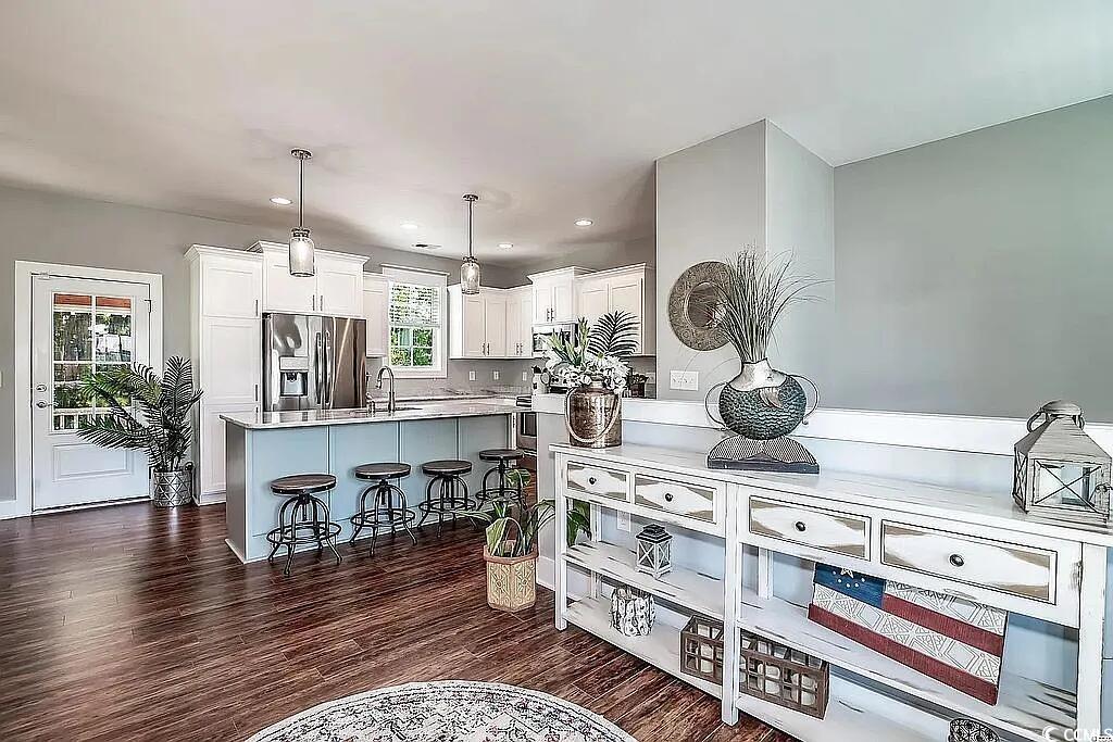 399 Lumbee Circle Pawleys Island, SC 29585 - Photo 4 of 30 Kitchen featuring pendant lighting, a breakfast bar, stainless steel fridge, dark wood-style flooring, and white cabinetry