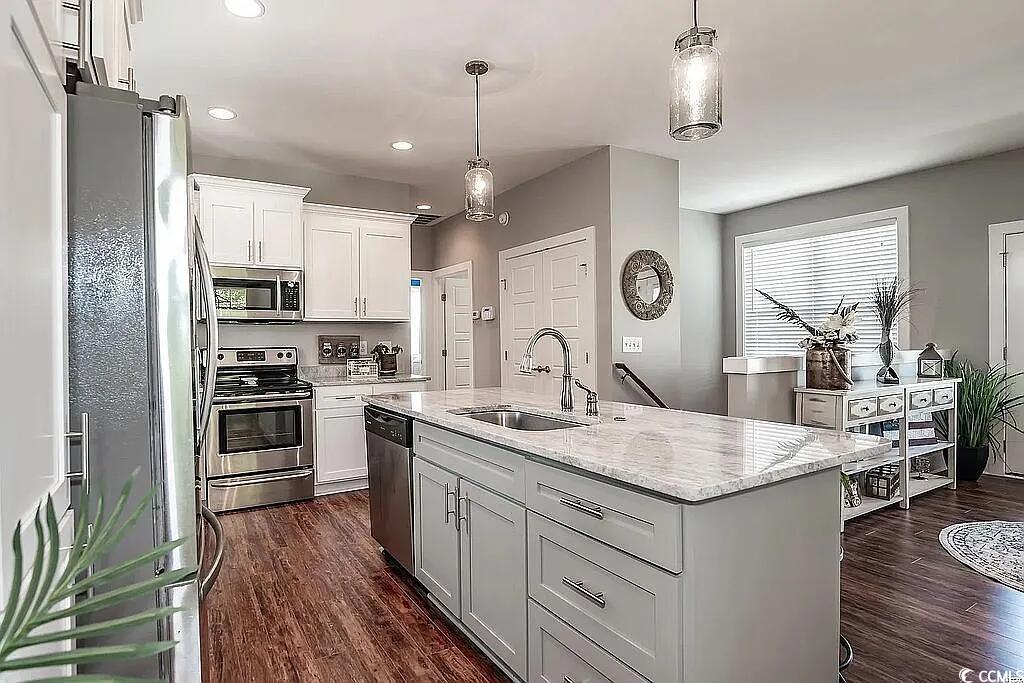 399 Lumbee Circle Pawleys Island, SC 29585 - Photo 10 of 30 Kitchen with stainless steel appliances, hanging light fixtures, white cabinetry, light stone countertops, and dark wood finished floors