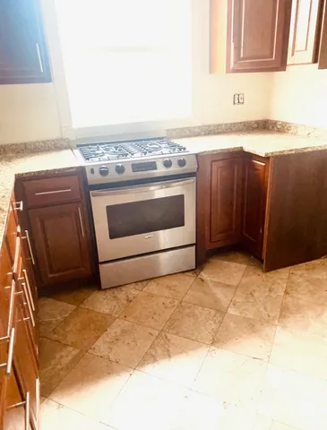 a kitchen with granite countertop a stove top oven and cabinets