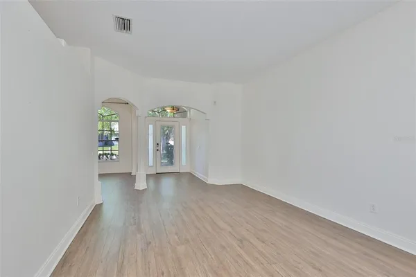 a view of an empty room with window and wooden floor