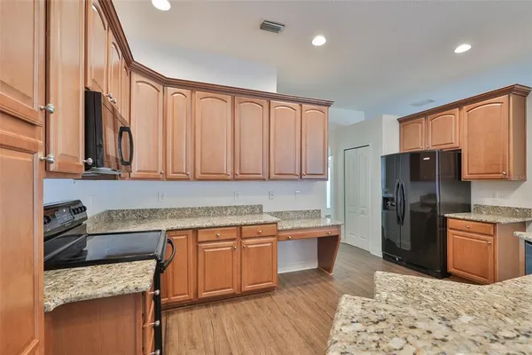 a kitchen with stainless steel appliances granite countertop a refrigerator a sink dishwasher a stove with wooden cabinets and floor