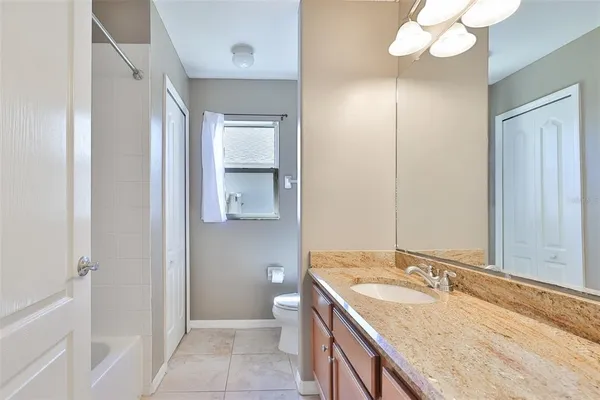 a bathroom with a granite countertop sink a toilet and a mirror