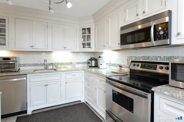 a kitchen with granite countertop white cabinets and stainless steel appliances