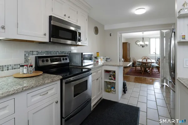 a kitchen with granite countertop a stove and a white cabinets