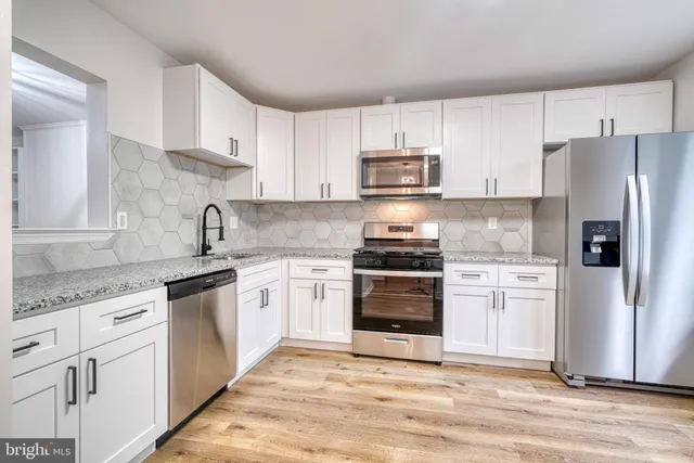 a kitchen with granite countertop white cabinets and stainless steel appliances