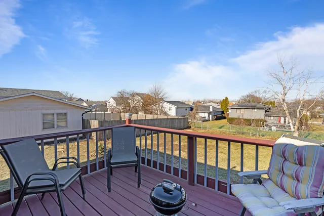 a view of a balcony with wooden chairs and barbeque grill