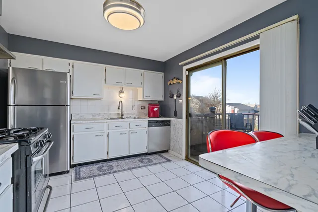 a kitchen that has a lot of white cabinets and stainless steel appliances