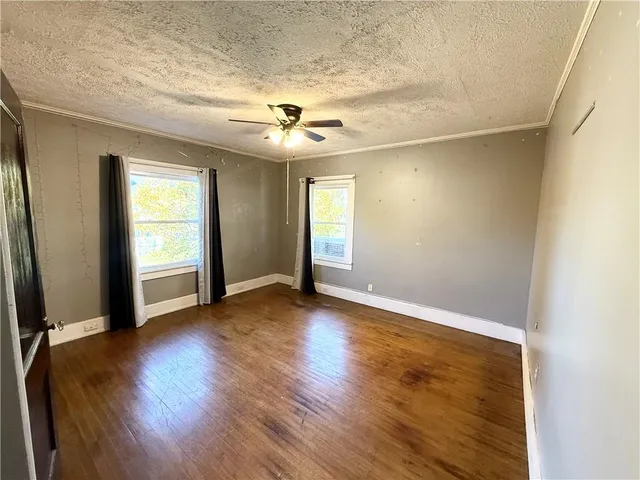 an empty room with wooden floor and windows