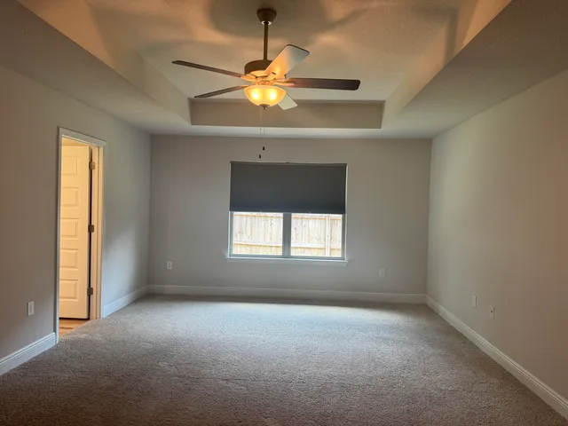 en empty room with windows and chandelier fan