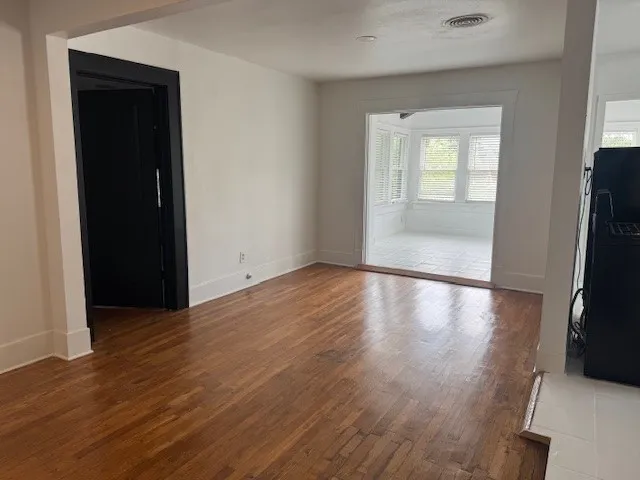 an empty room with wooden floor cabinet and windows