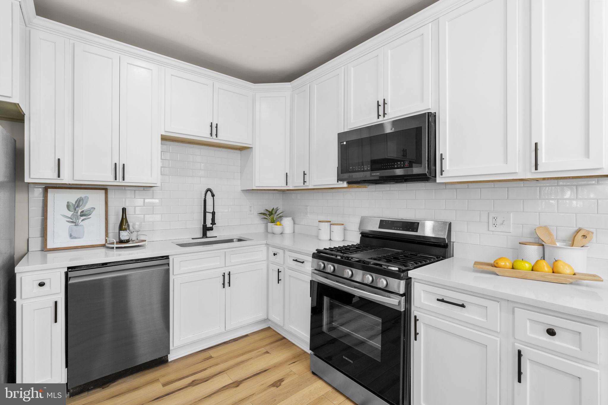 3111 Foster Avenue Baltimore, MD 21224 - Photo 6 of 28 a kitchen with stainless steel appliances granite countertop a sink a stove and a microwave