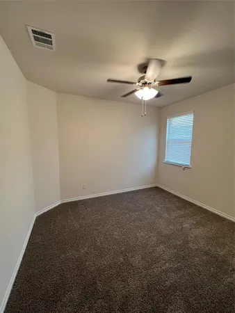 an empty room with windows and chandelier fan