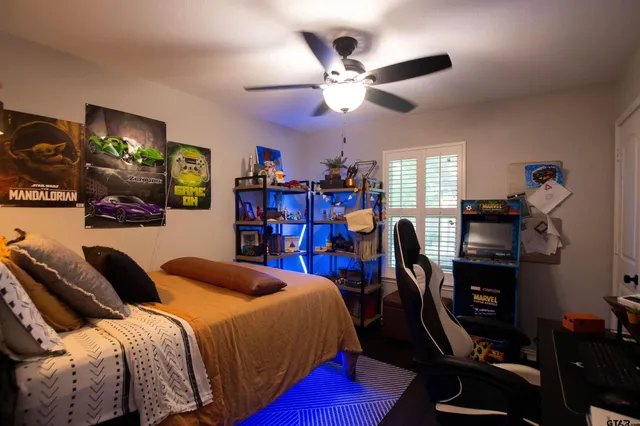 a bedroom with a bed a desk and chair with the bookshelf