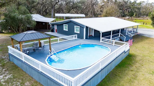 a view of a house with pool and chairs