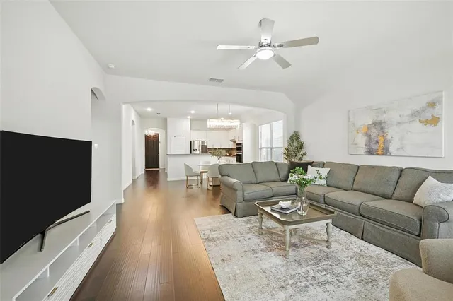 a living room with furniture a ceiling fan and a flat screen tv