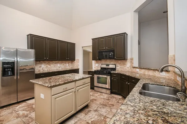 a view of a livingroom with a fireplace a ceiling fan a kitchen a refrigerator and a stove top oven