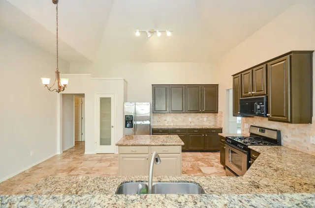 a large kitchen with kitchen island granite countertop a sink and counter space