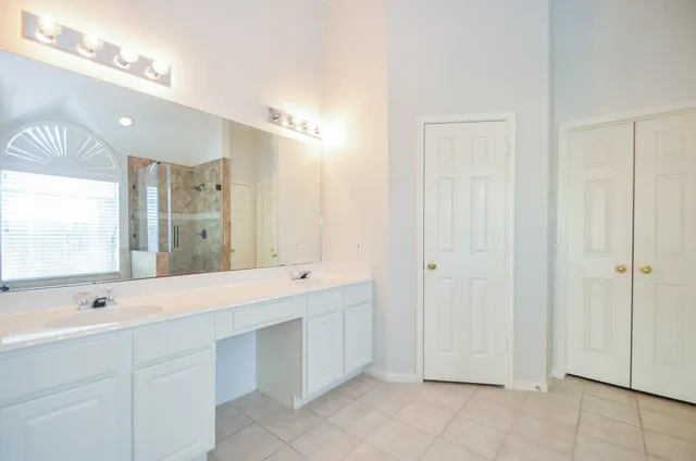 a spacious bathroom with a double vanity sink a mirror and a shower