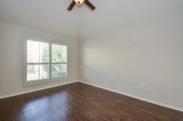 an empty room with wooden floor cabinet and windows
