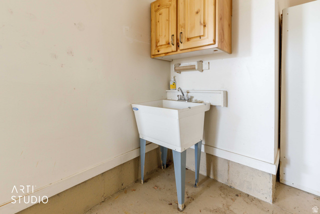 2327 Bluff Ridge Drive Syracuse, UT 84075 - Photo 43 of 66 Utility sink area featuring a white basin with metal legs, chrome faucet, and overhead wood cabinetry