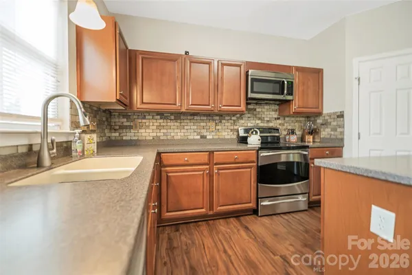 a kitchen with stainless steel appliances granite countertop a table chairs stove and refrigerator