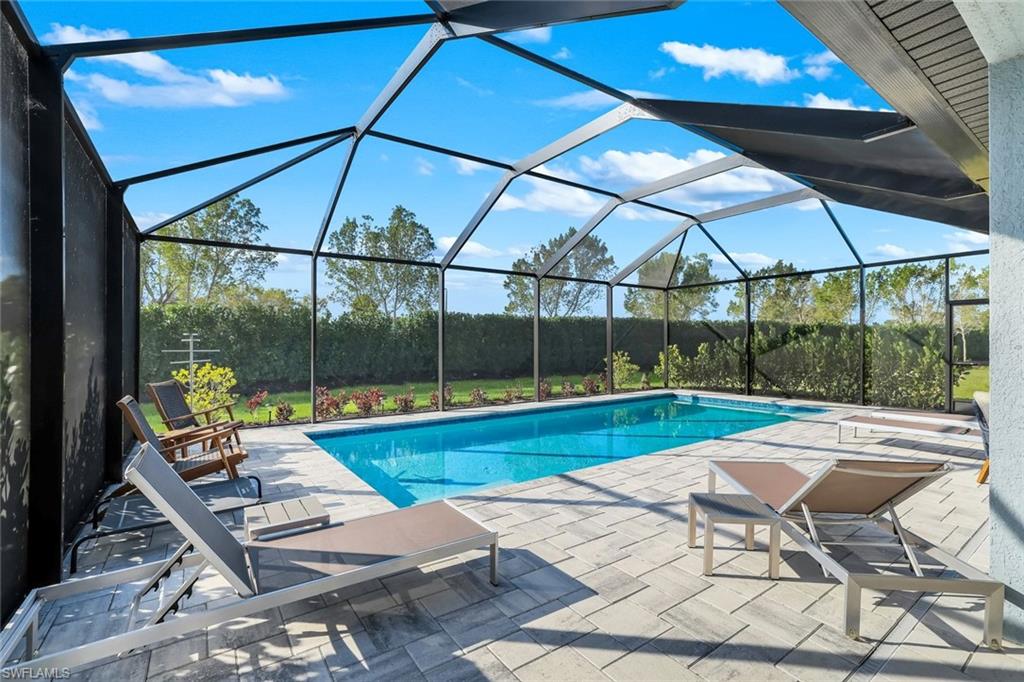 a view of swimming pool with lawn chairs under an umbrella