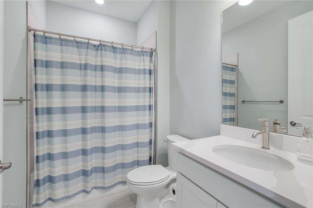 1944 Yellowfin Circle Naples, FL 34114 - Photo 23 of 36 a bathroom with a sink a toilet and shower curtain