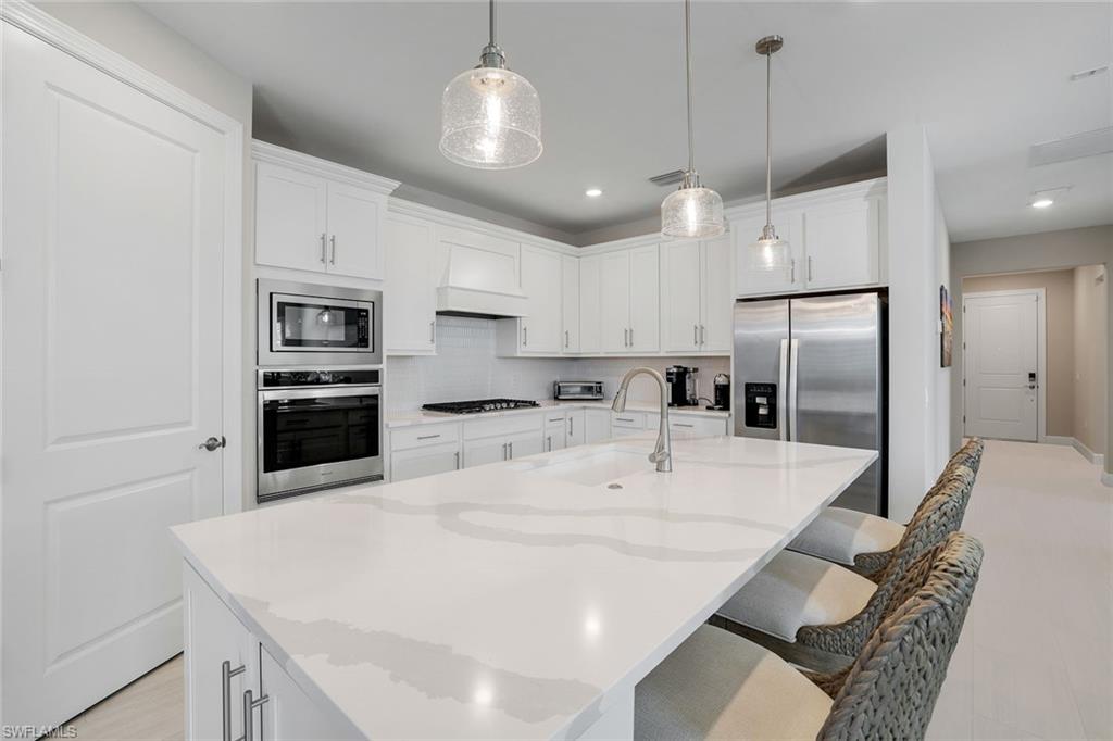 1944 Yellowfin Circle Naples, FL 34114 - Photo 4 of 36 a large kitchen with kitchen island a stove a sink a center island and cabinets