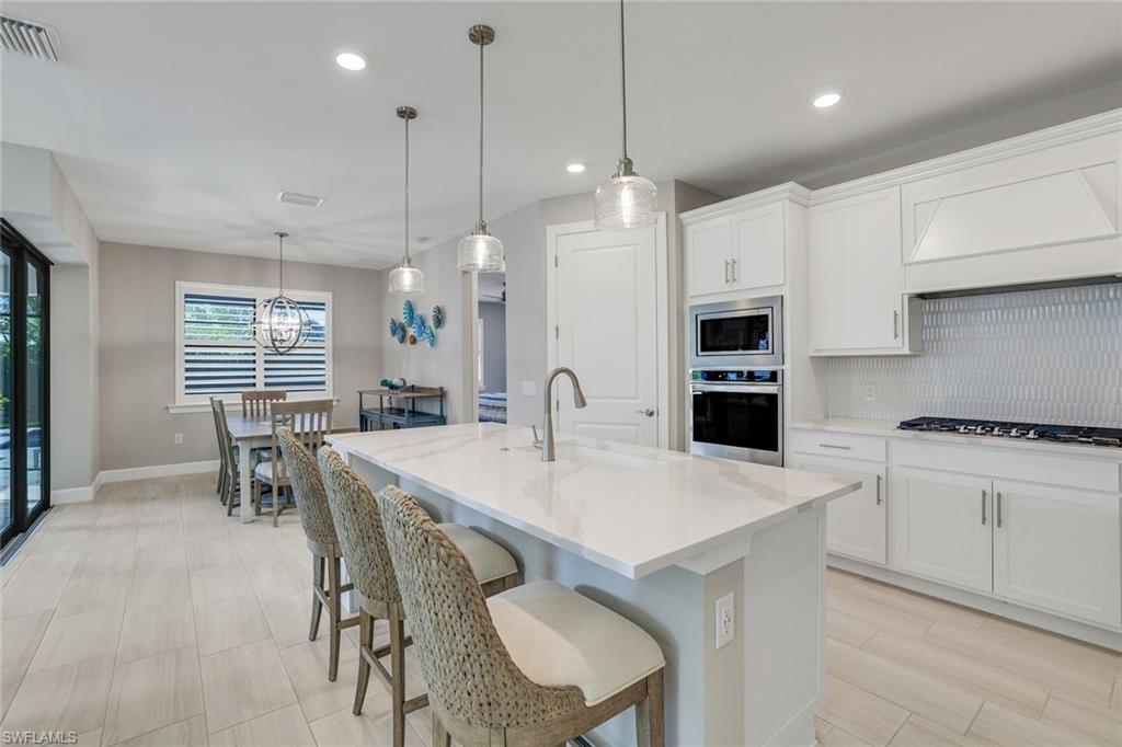 1944 Yellowfin Circle Naples, FL 34114 - Photo 10 of 36 a large kitchen with stainless steel appliances kitchen island a table chairs and a refrigerator