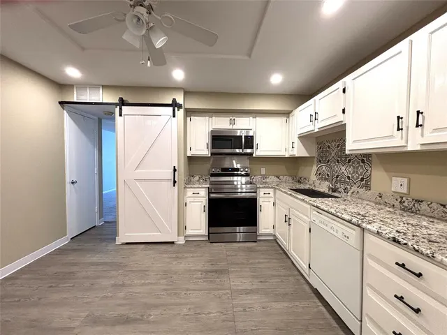 a kitchen with granite countertop a refrigerator stove and microwave