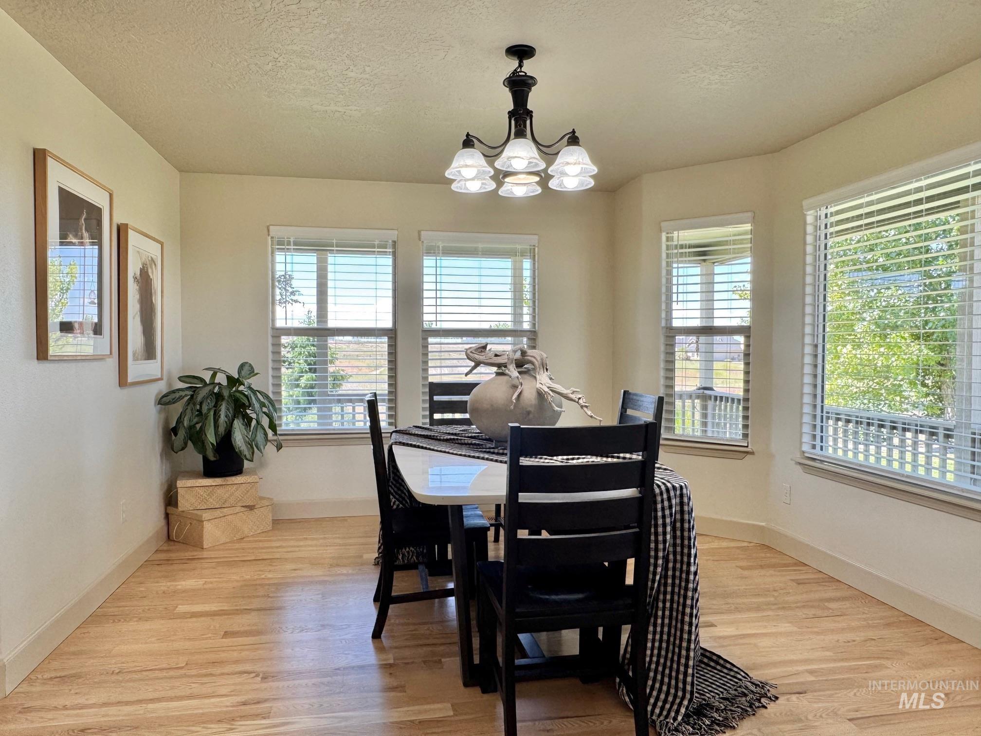 9299 Kemp Road Middleton, ID 83644 - Photo 16 of 50 Bay window with multiple windows, wood-finish flooring, and a chandelier lighting fixture