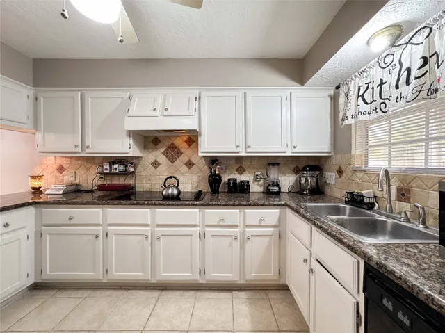 a kitchen with granite countertop white cabinets and sink