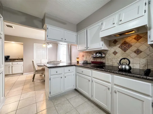 a kitchen with granite countertop white cabinets and stainless steel appliances
