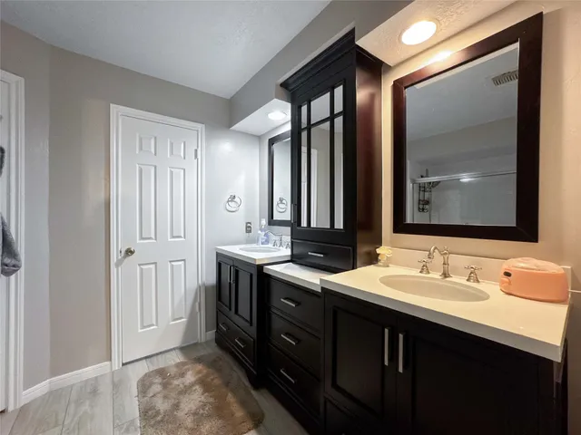 a bathroom with a double vanity sink a large mirror and shower