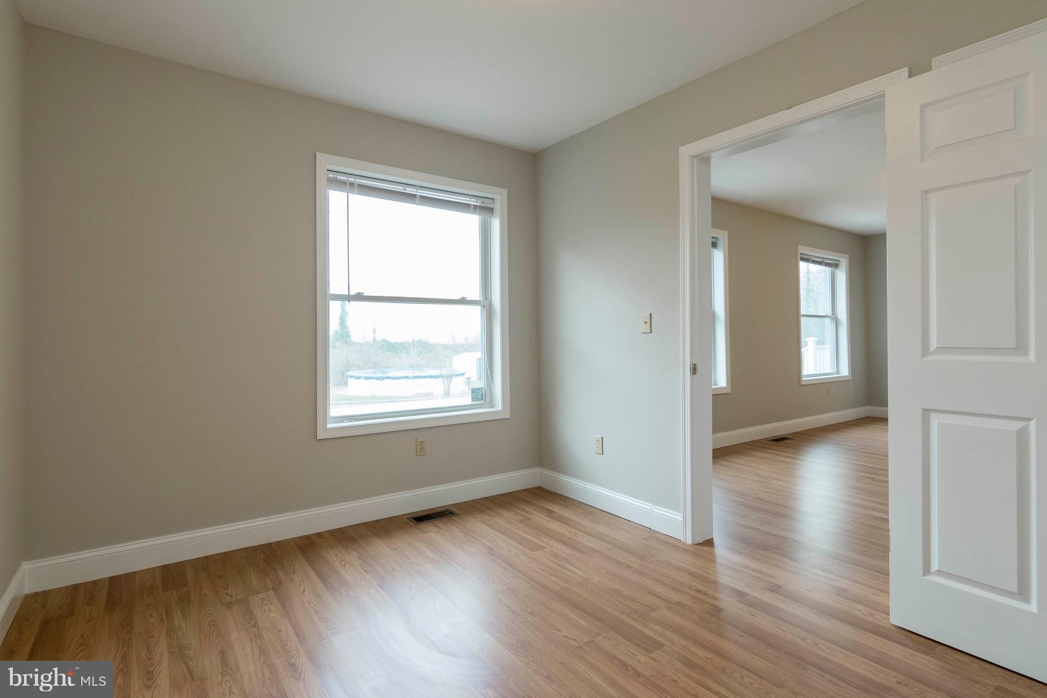 5901 Shady Spring Avenue Baltimore, MD 21237 - Photo 13 of 30 an empty room with wooden floor and windows